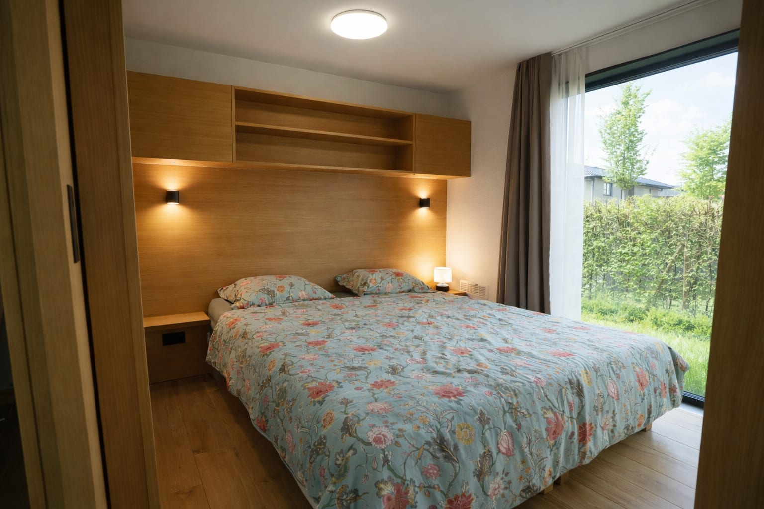 Schlafraum mit nordischer Kiefer und großer Fensterfront zum Garten