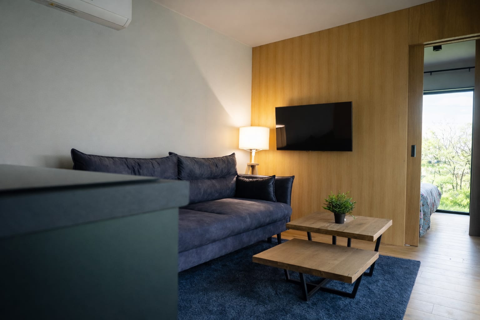 Wohnraum mit nordischer Kiefer, dunkelblauem Sofa und warmem Licht